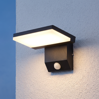 Black outdoor LED wall light with motion sensor installed on a white wall